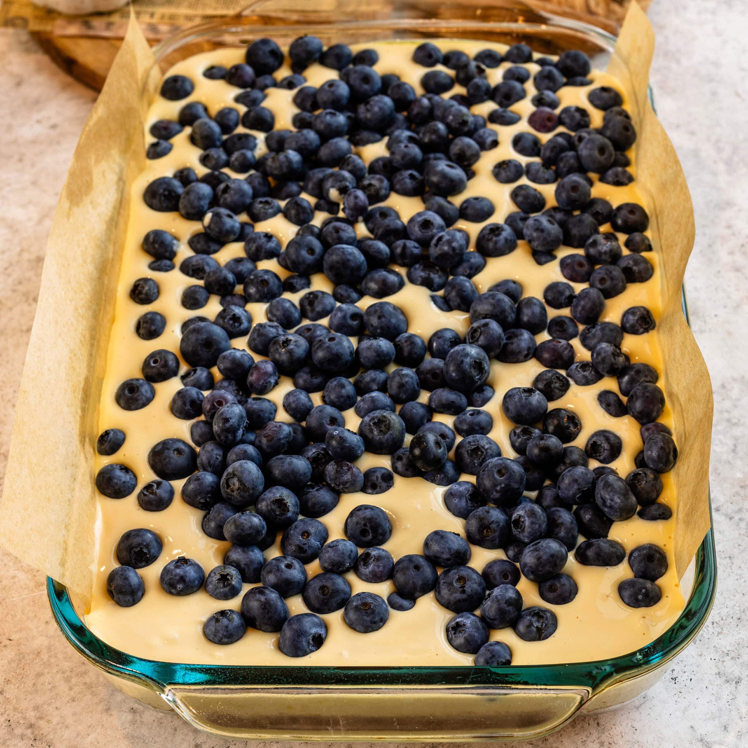 The blueberry layer being added to the cheesecake layer.