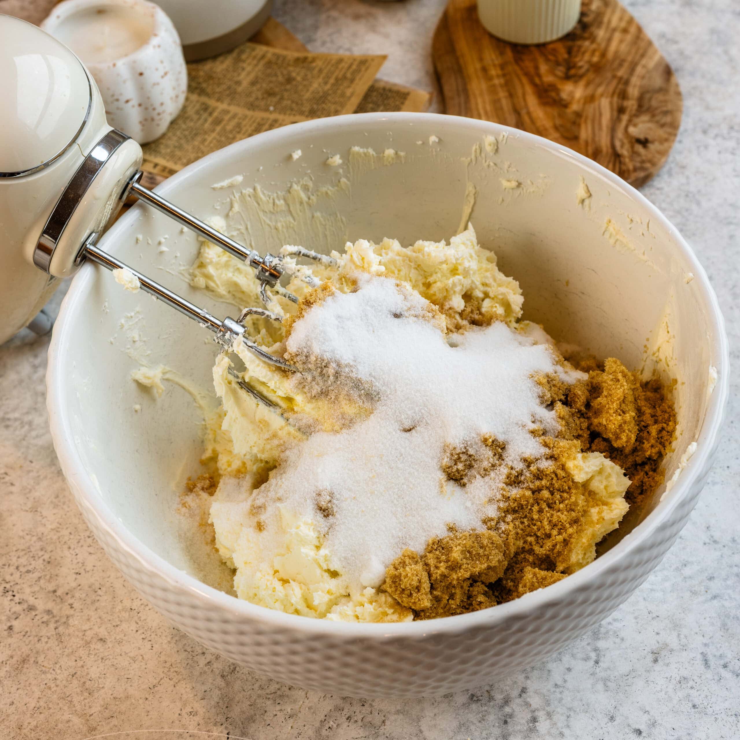 Butter, cream cheese, granulated sugar, and brown sugar thrown in a mixing bowl and ready to be whipped into a cheesecake filling.