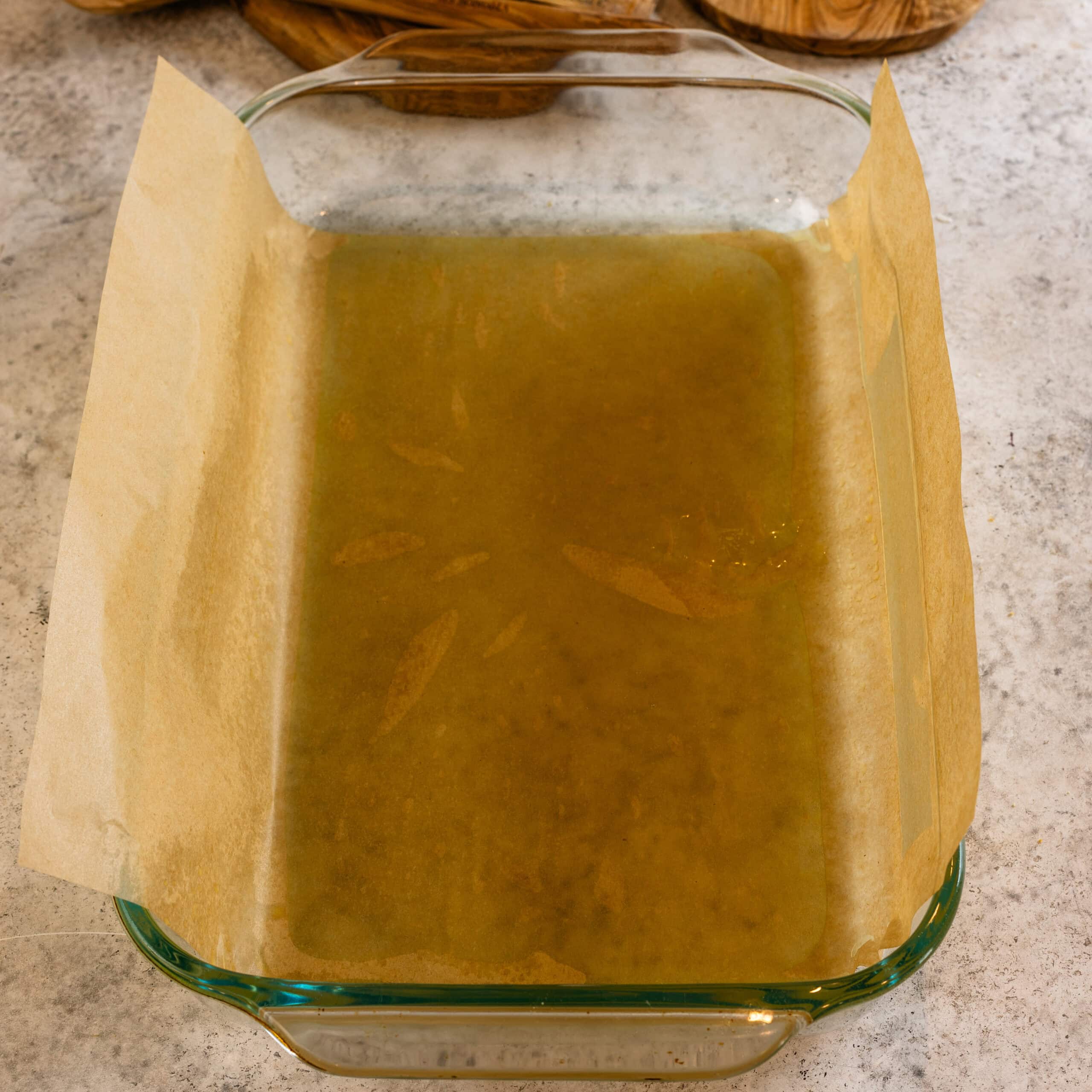 A greased and parchment lined 9x13" pan ready for blueberry cheesecake bars.