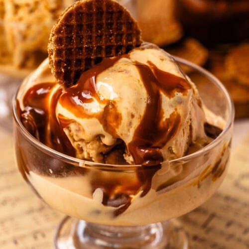 Dulce de leche ice cream with thick ribbons of caramelized dulce de leche in a glass dessert bowl topped with a cookie.