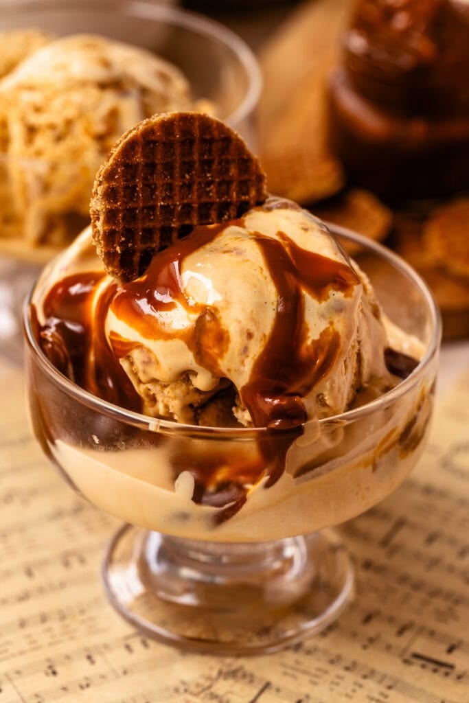 Dulce de leche ice cream with thick ribbons of caramelized dulce de leche in a glass dessert bowl topped with a cookie.