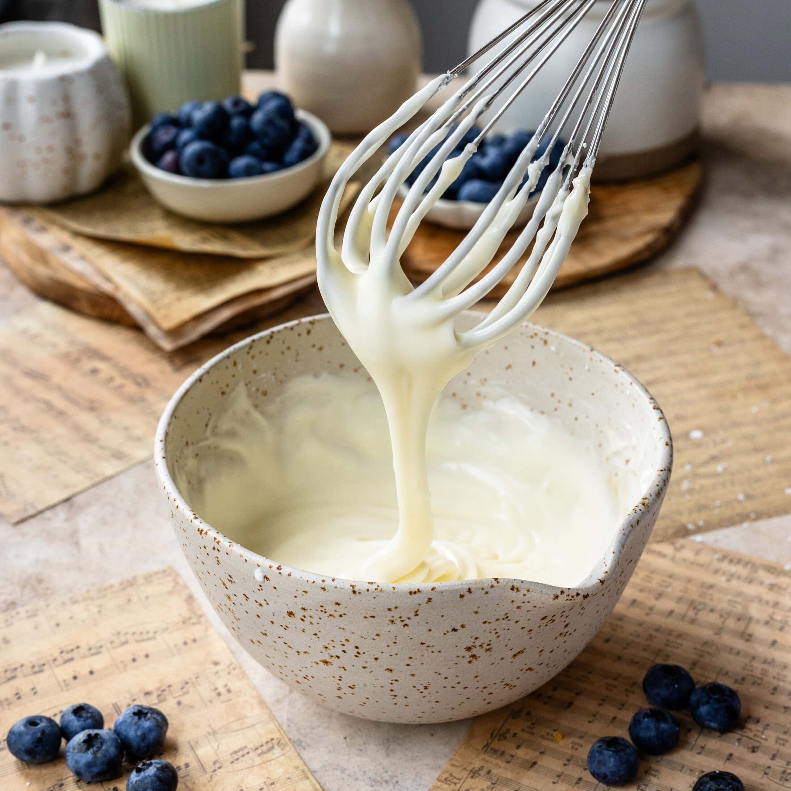 Luscious and silky cream cheese glaze for blueberry crumble cheesecake bars.