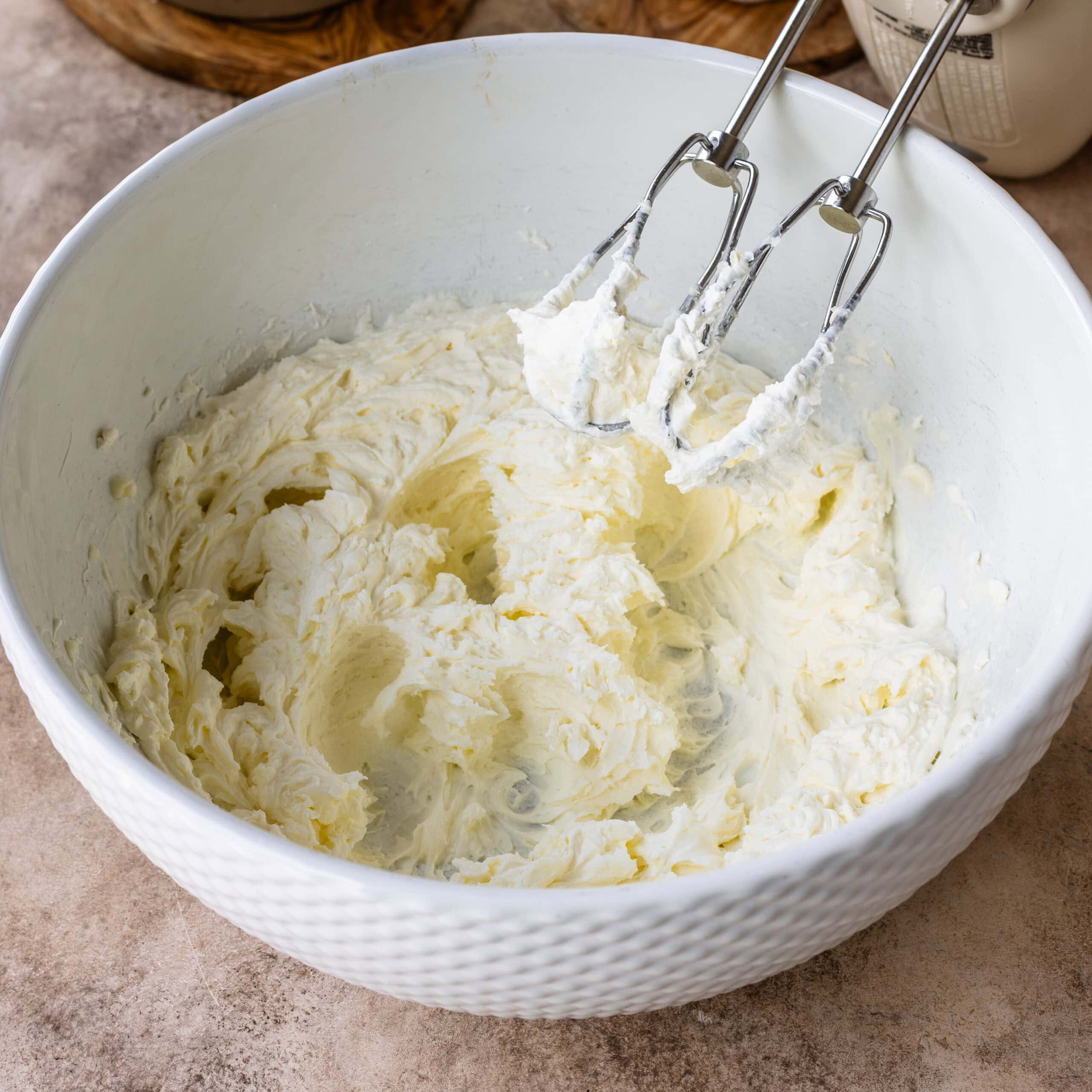 Whipped mascarpone in a white mixing bowl.