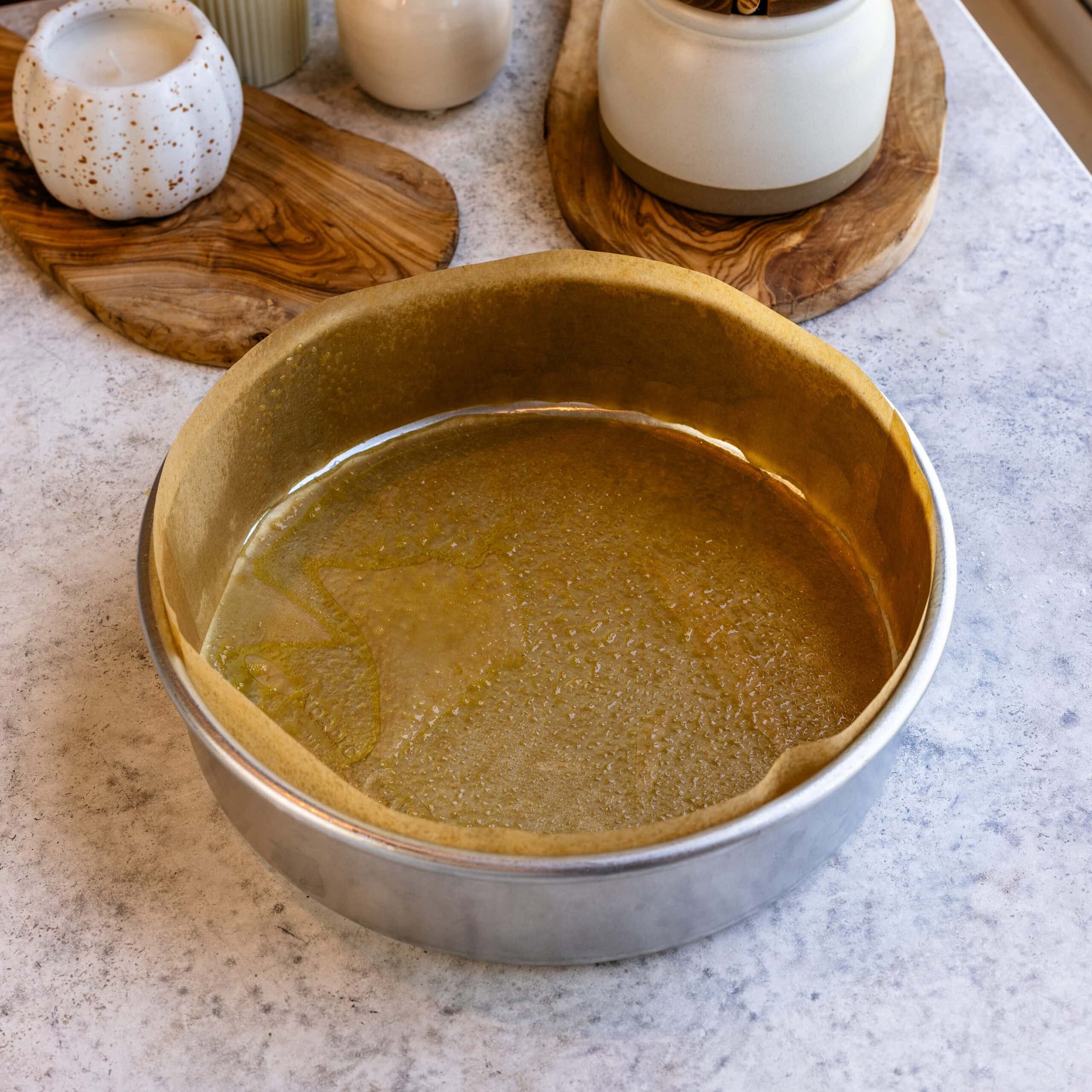 A greased and parchment lined cake pan ready to be filled with olive oil cake batter.