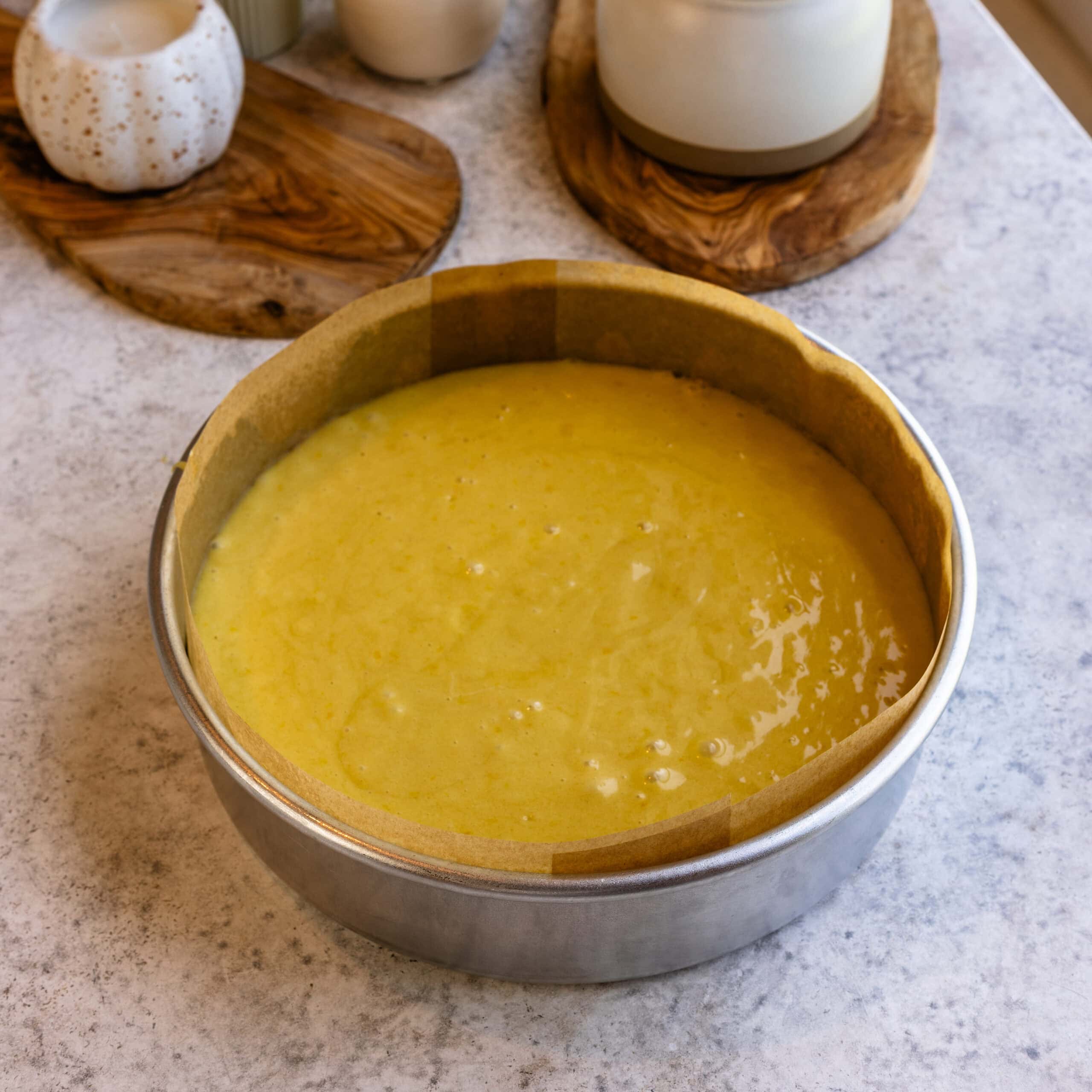 Olive oil cake batter in a large cake pan ready to be baked in the oven.