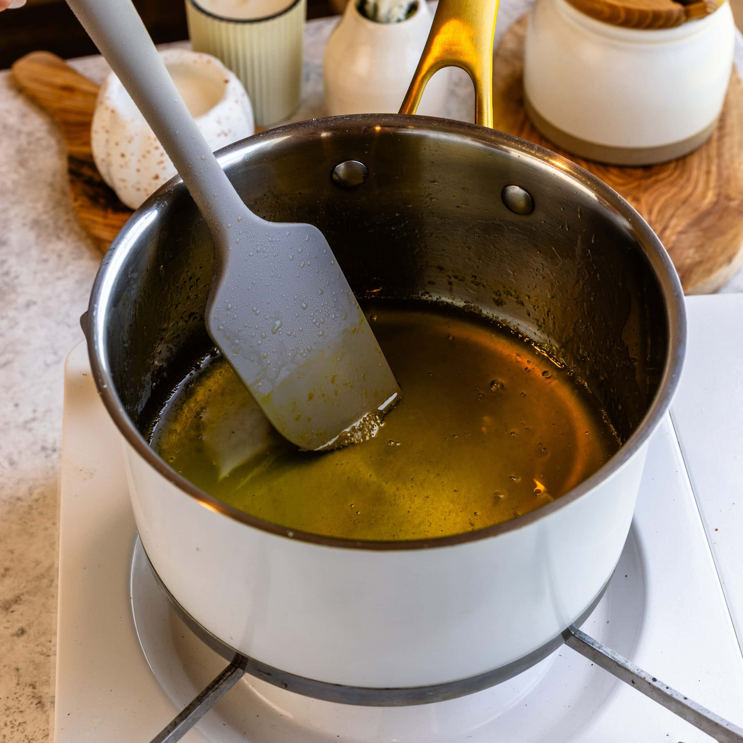 Orange simple syrup being heated on the stove in a medium saucepan.