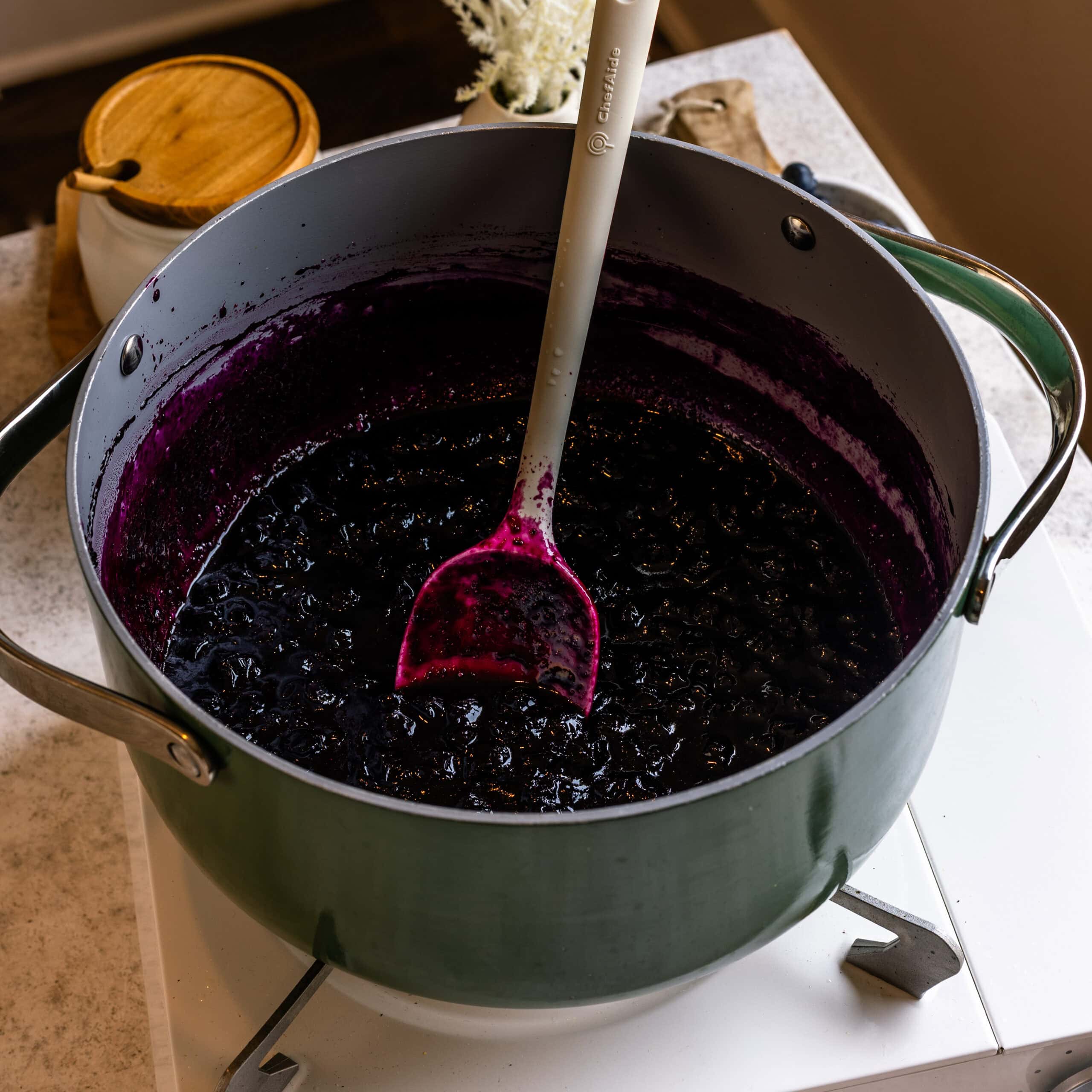 Reduced blueberry sauce in a saucepan on the stove.