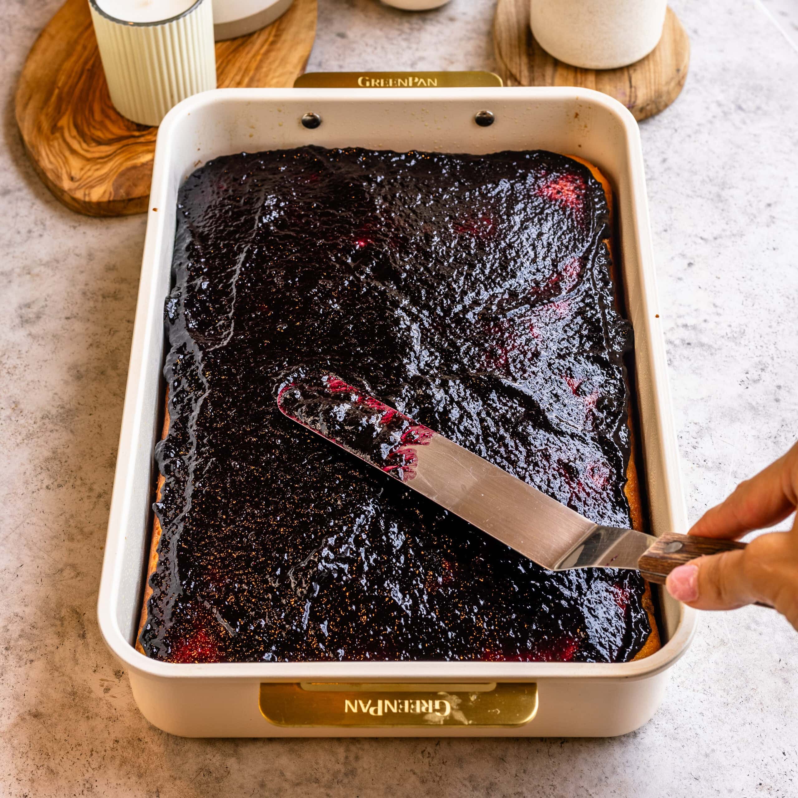 Blueberry sauce being smeared all over the blueberry cake.