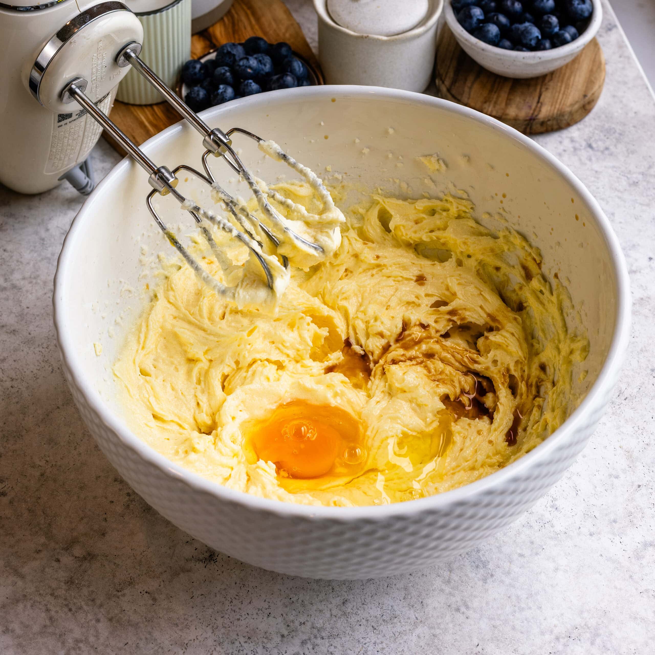 An egg and vanilla being added to the blueberry sheet cake batter.