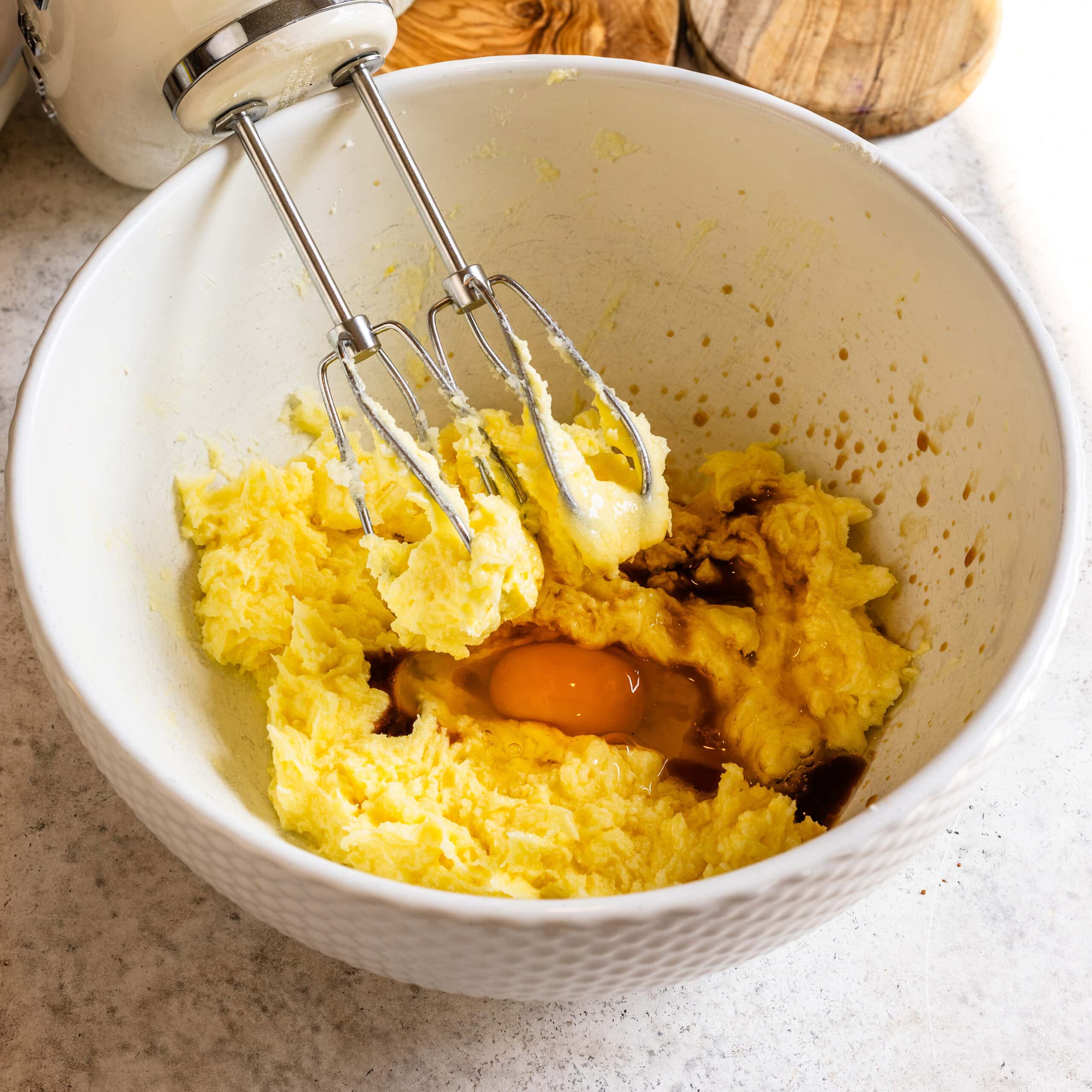 Creamy mashed potatoes with an egg and seasonings in a white bowl.