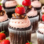 Chocolate Strawberry Cupcakes filled with strawberry sauce and topped with strawberry cream cheese frosting, chocolate ganache, chocolate shavings, and fresh strawberries.