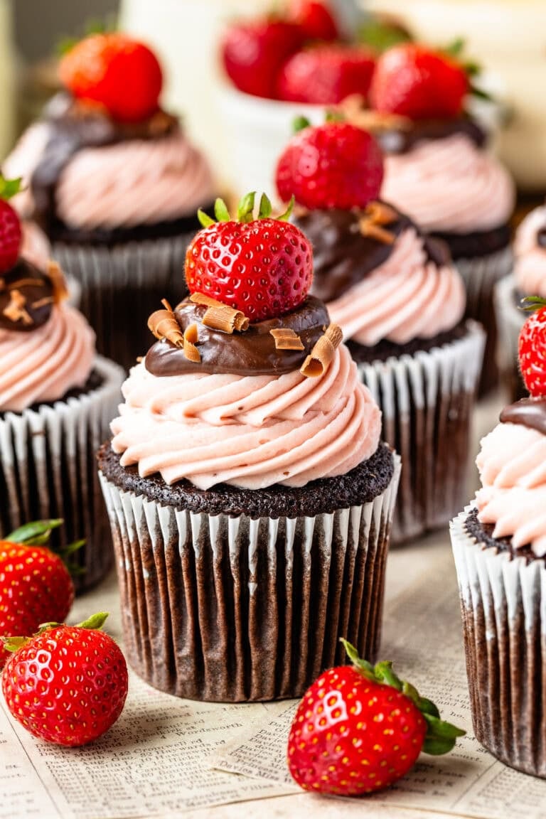 Chocolate Strawberry Cupcakes filled with strawberry sauce and topped with strawberry cream cheese frosting, chocolate ganache, chocolate shavings, and fresh strawberries.
