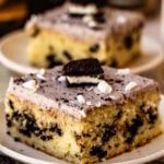 Slice of Cookies and Cream Sheet Cake with Oreo pieces, Oreo cream cheese frosting, and white chocolate shavings.