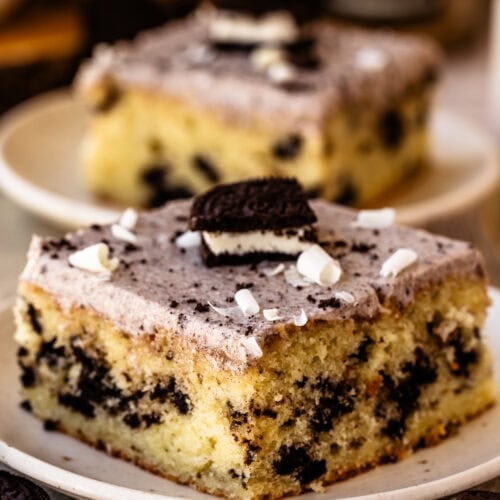Slice of Cookies and Cream Sheet Cake with Oreo pieces, Oreo cream cheese frosting, and white chocolate shavings.