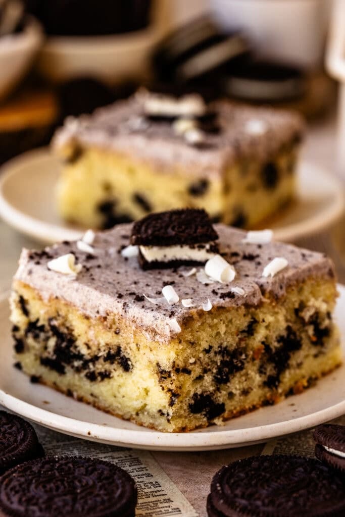 Slice of Cookies and Cream Sheet Cake with Oreo pieces, Oreo cream cheese frosting, and white chocolate shavings.