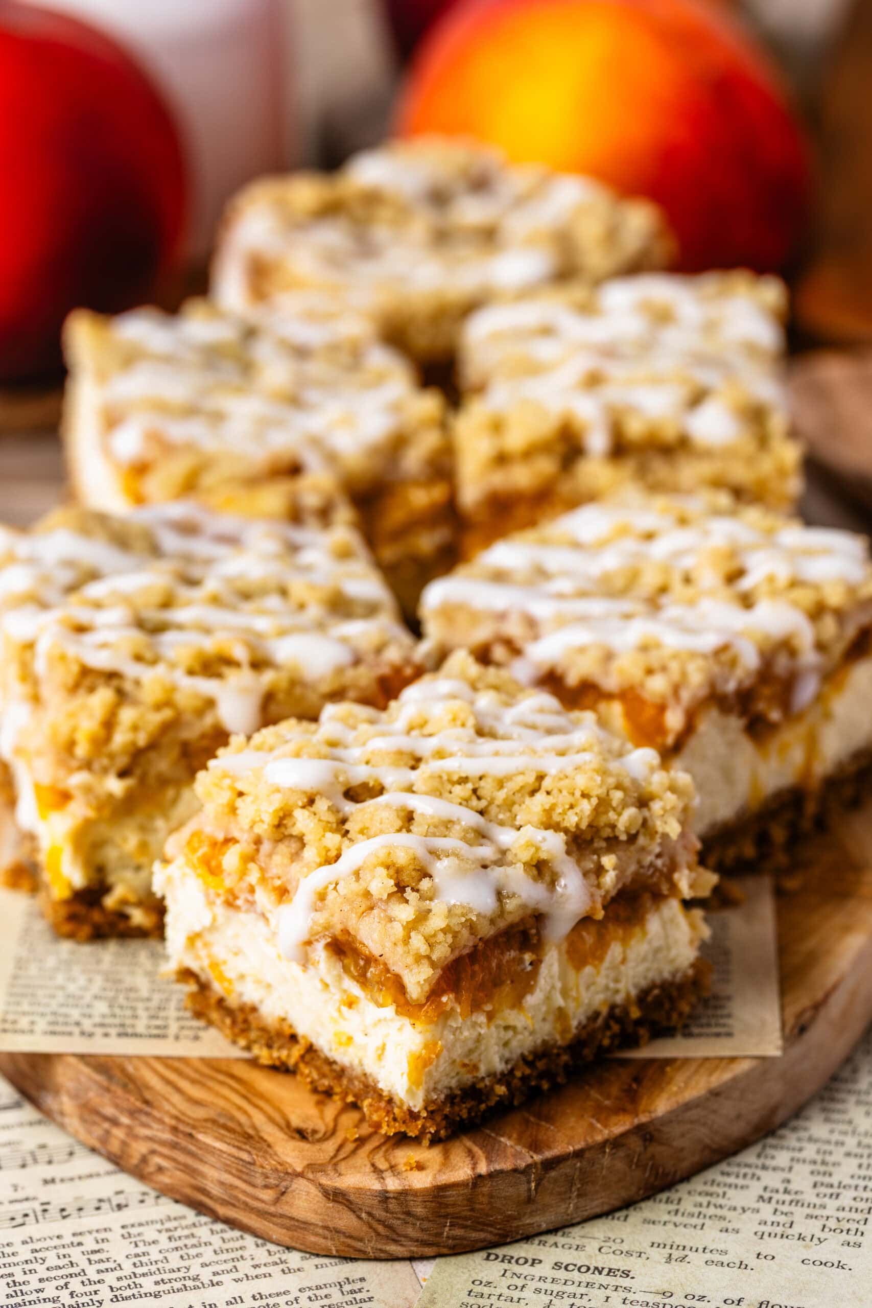 Peach Crumble Cheesecake Bars with creamy cheesecake, spiced peach filling, buttery crumble, and cream cheese glaze.