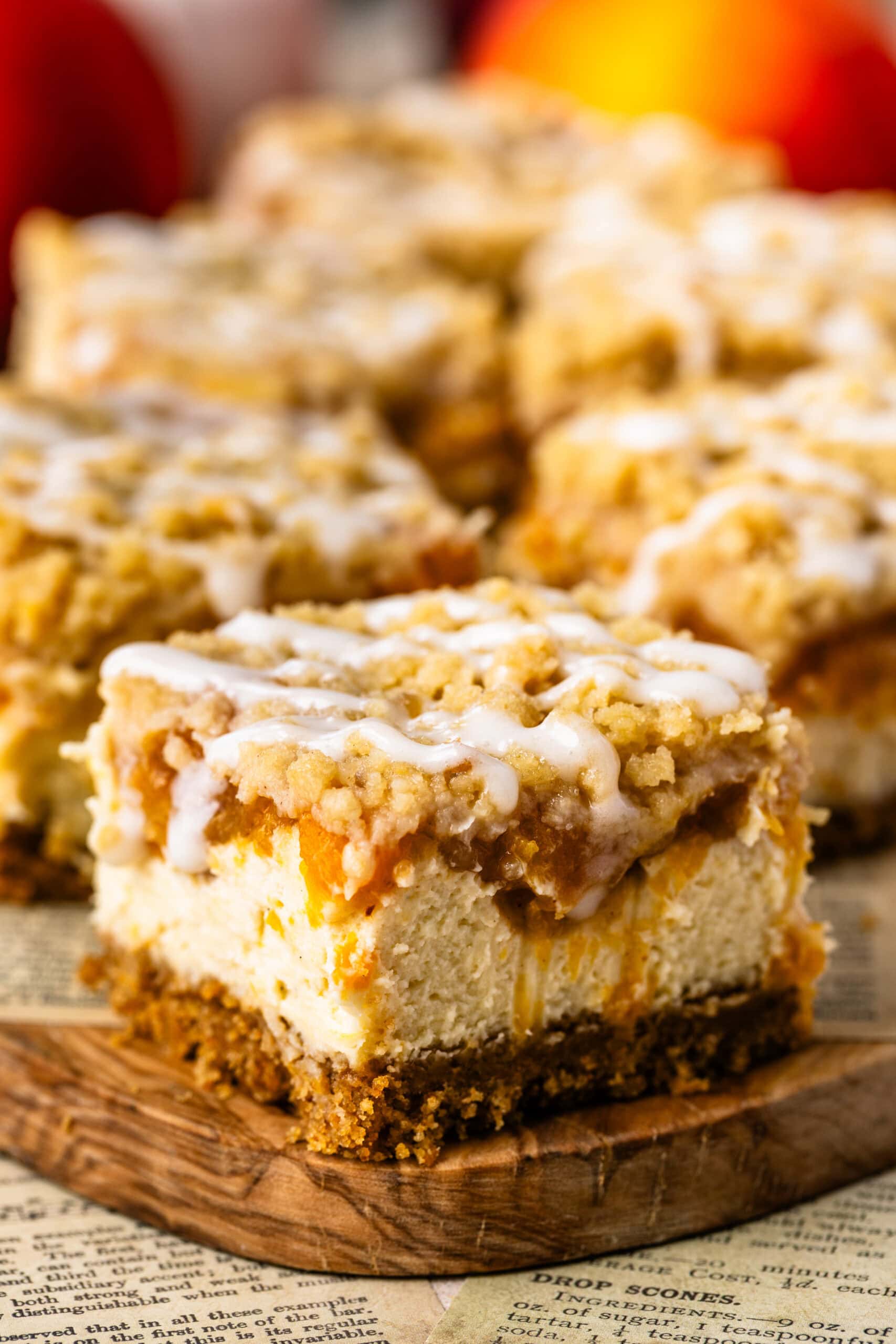 Peach Crumble Cheesecake Bar with creamy cheesecake, spiced peach filling, buttery crumble, and cream cheese glaze.