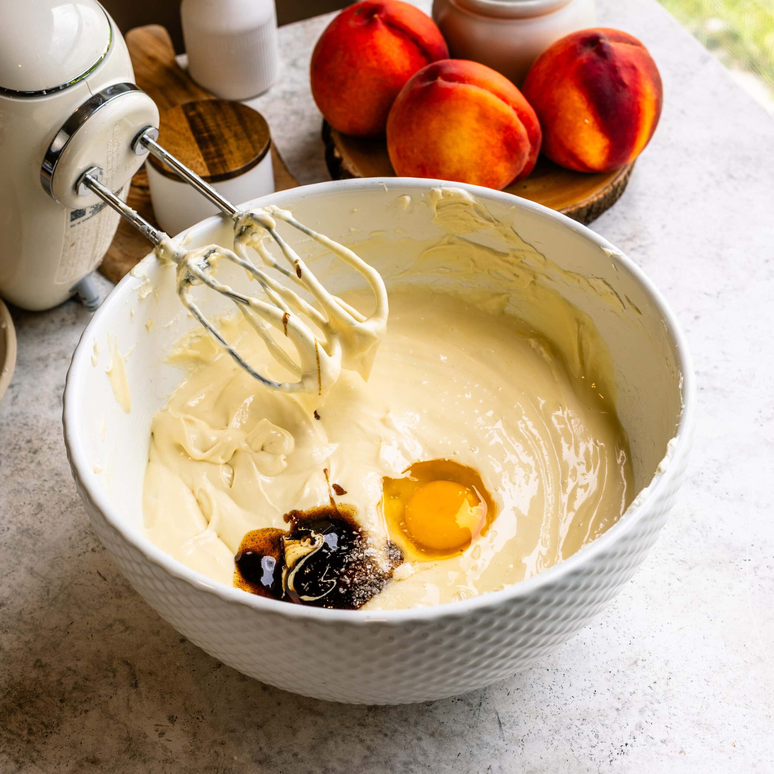 Egg and vanilla being added to the cheesecake batter.