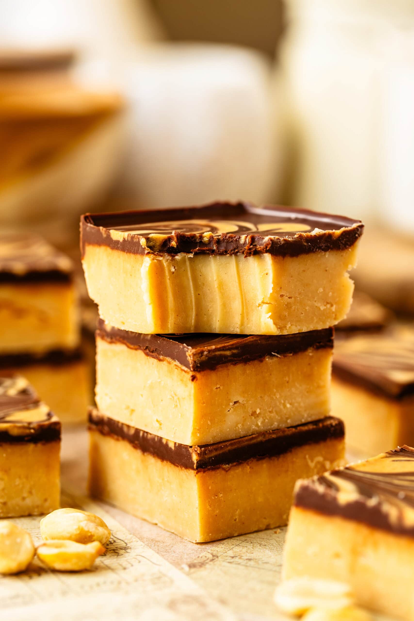 Peanut butter fudge squares with a chocolate layer and peanut butter swirl on top, stacked together.