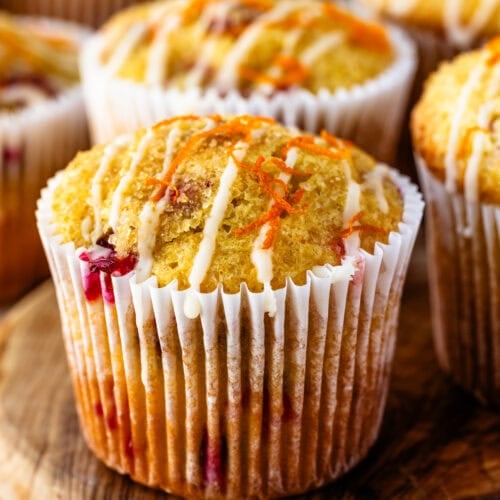 Close-up of cranberry orange muffins drizzled with sweet orange glaze and sprinkled with orange zest.