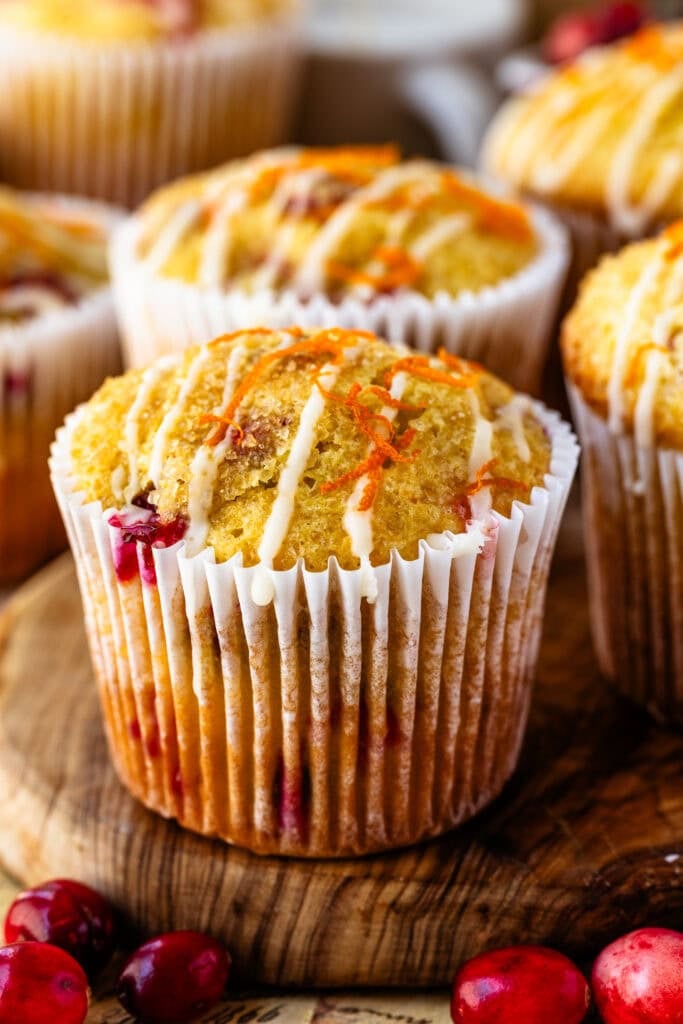 Close-up of cranberry orange muffins drizzled with sweet orange glaze and sprinkled with orange zest.